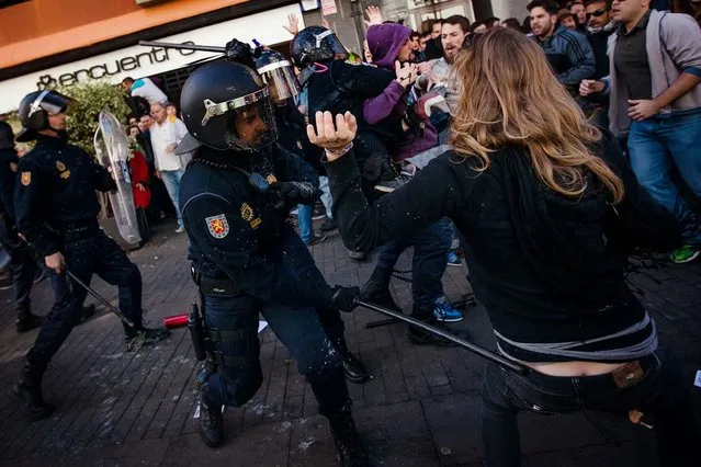Police officers use their batons against demonstrators during clashes following a protest in Santa Cruz de Tenerife in the Canary Islands, Spain, on January 25, 2014. The protest was targeted at Education Minister José Ignacio Wert, who was attending the inauguration of a cathedral and is unpopular for his education reforms. (Photo by Andres Gutierrez/Associated Press)