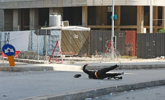 A man falls upon being shot as he was preparing to fire a rocket-propelled grenade during gunfire in Beirut, Lebanon on October 14, 2021. (Photo by Aziz Taher/Reuters)