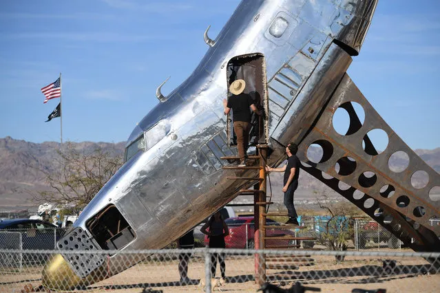 People visit an installation sculpture of a crashed plane by artist Randy Polumbo, on the first day of the Bombay Beach Biennale, March 22 2019 in Bombay Beach, California. The tiny desert town, once a thriving resort along the Salton Sea, is among the poorest communities in California, but the remote hamlet is experiencing a rebirth of sorts as a result of the annual gathering called the Bombay Beach Biennale which organizers describe as an interactive art gathering. (Photo by Robyn Beck/AFP Photo)