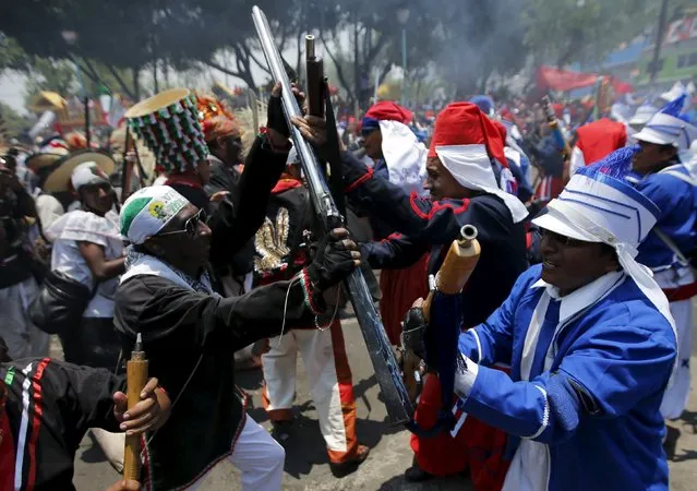 Mexicans wearing period costumes re-enact the battle of Puebla, in Mexico City May 5, 2015. The battle marked the defeat of French forces by Mexican troops and local Indians in the central state of Puebla in 1862. During the re-enactment, participants fired homemade shotguns loaded with gunpowder and hundreds of men dressed as female Indian peasants with blackened faces, straw hats and embroidered blouses fought mock battles against French invaders in white bloomers. (Photo by Henry Romero/Reuters)