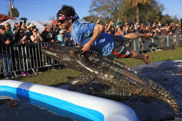 Ben Green, of St. Augustine, flies into the pool on his inflatable alligator to find the hidden lizard at the bottom of the pool in the “Evading Arrest Obstacle Course” during the inaugural Florida Man Games, Saturday, February 24, 2024, at Francis Field in St. Augustine, Fla. (Photo by Corey Perrine/The Florida Times-Union via AP Photo)