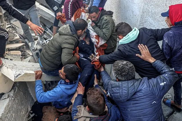 Palestinians evacuate the body of a boy from the rubble of a house destroyed in an overnight Israeli air strike in east Khan Yunis in the southern Gaza Strip on February 26, 2024, amid continuing battles between Israel and the Palestinian militant group Hamas. (Photo by Said Khatib/AFP Photo)