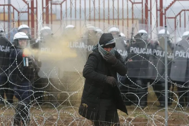 A Polish law enforcement officer uses tear gas, as migrants attempt to cross the Belarusian-Polish border at Bruzgi – Kuznica checkpoint in the Grodno region, Belarus on November 16, 2021. (Photo by Leonid Scheglov/BelTA/Handout via Reuters)
