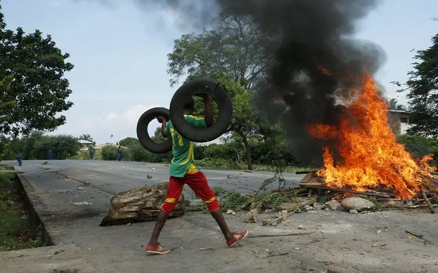 A protester carries tyres to add to a burning barricade during a protest against Burundi President Pierre Nkurunziza and his bid for a third term in Bujumbura, Burundi May 21, 2015. (Photo by Goran Tomasevic/Reuters)