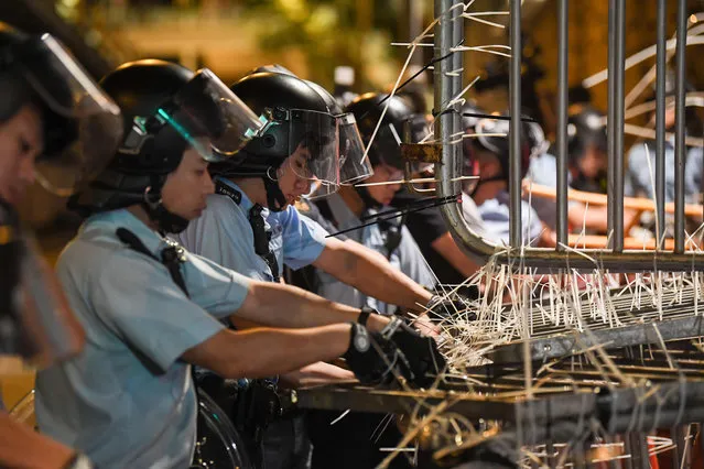 Police clear barricades which were set up by protesters outside the police headquarters in Hong Kong early on June 22, 2019. Hong Kong police on June 22 vowed to pursue the ringleaders of a 15-hour blockade of their headquarters which involved thousands of anti-government demonstrators as a push to oust the city's pro-Beijing leader evolves. (Photo by Anthony Wallace/AFP Photo)