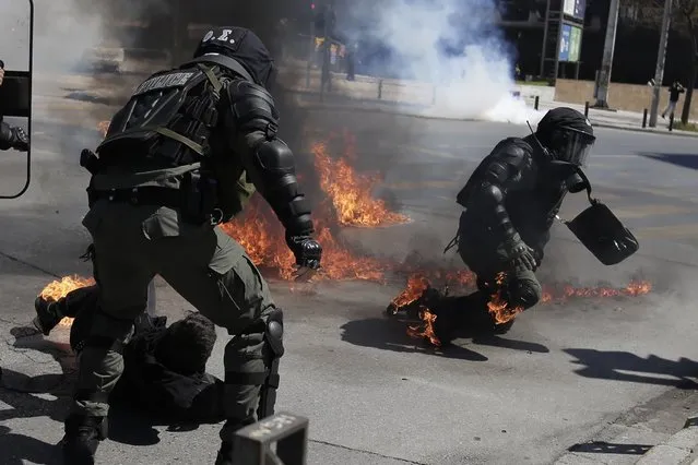 A protester, bottom, and riot policeman react after catching fire from a gasoline bomb during a protest in the the northern city of Thessaloniki, Greece, Thursday, April 15, 2021. The protester was arrested on suspicion of throwing a gasoline bomb, authorities said. He was taken to hospital after being injured during his arrest, apparently when a gasoline bomb landed nearby, catching both the protester and the riot policeman detaining him. Clashes between small groups of demonstrators and police broke out in the northern Greek city of Thessaloniki at the end of a march to protest a new law allowing the policing of university campuses. (Photo by Achilleas Chiras/AP Photo)