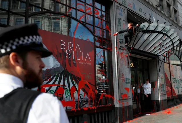 An activist splashes red paint over the embassy's facade during Extinction Rebellion climate change protest in front of Brazilian Embassy in London, Britain, August 13, 2019. (Photo by Peter Nicholls/Reuters)