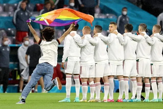 A person waving the rainbow flag runs on the pitch as the players line up for the national anthems the UEFA EURO 2020 Group F football match between Germany and Hungary at the Allianz Arena in Munich on June 23, 2021. (Photo by Alexander Hassenstein/Pool via AFP Photo)
