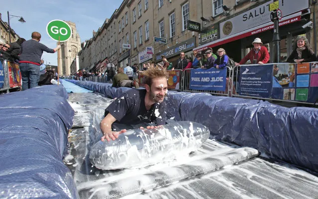 A participant on a lilo slides down a giant water slide that has been installed down Park Street on May 4, 2014 in Bristol, England. (Photo by Matt Cardy/Getty Images)