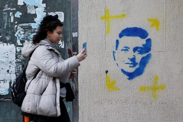 A woman uses a phone in front of a stencil-graffiti with the image of Ukrainian President Volodymyr Zelenskiy, amid Russian invasion on Ukraine, in Podgorica, Montenegro on March 8, 2022. (Photo by Stevo Vasiljevic/Reuters)