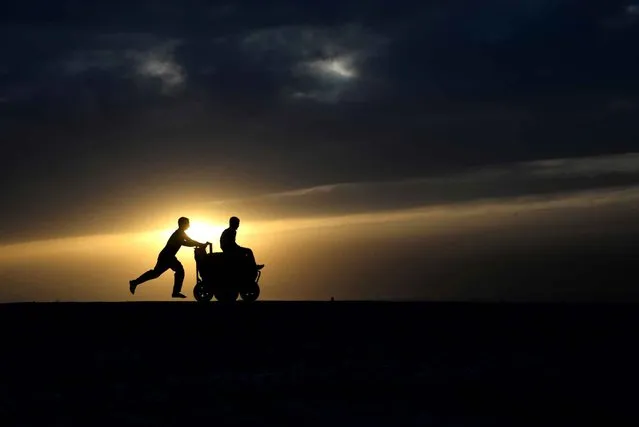 An Afghan youth pushes a friend on a ice-cream cart, as the sun sets on the outskirts of Mazar-i- Sharif on May 16, 2014. Afghanistan remains at war, with civilians among the hardest hit, as the Taliban wage an increasingly bloody insurgency against the government. (Photo by Farshad Usyan/AFP Photo)