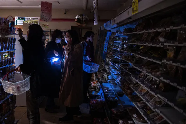 People shop in a store in a residential area during a power outage in Koto district in Tokyo on March 16, 2022, after a powerful 7.3-magnitude quake jolted east Japan. A powerful 7.3-magnitude quake jolted eastern Japan on the night of March 16, 2022, rattling the capital Tokyo and prompting a tsunami advisory for parts of the northeast coast, the Japan Meteorological Agency said. (Photo by Philip Fong/AFP Photo)
