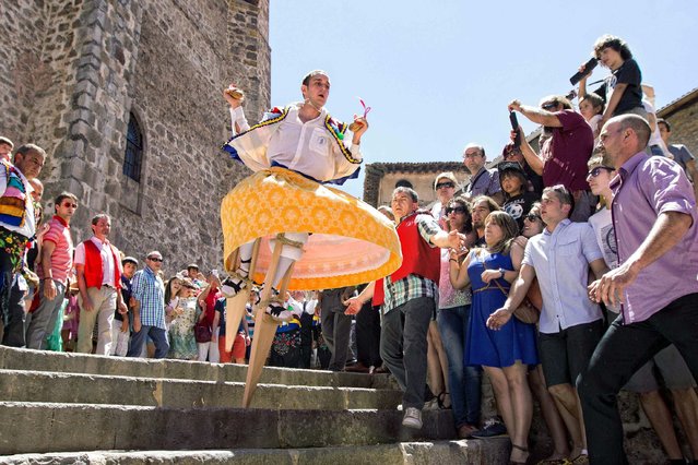 A resident takes part in a “colorful dance” onto stilts through a slope as part of a festival called “The Anguiano Dancers” in Anguiano, La Rioja, northern Spain, 22 July 2014.  The dancers walk down a slope turning like a human spinning top onto 45 centimeters high stilts to worship the town's patron, Mary Magdalene, in a tradition dated back to 1603. (Photo by Raquel Manzanares/EPA)