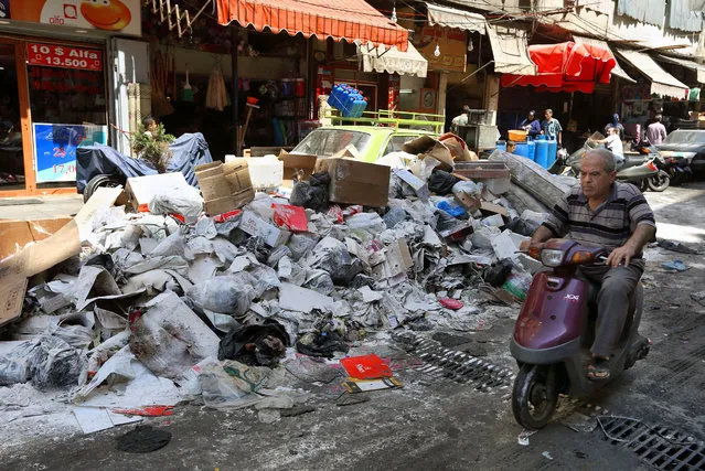 A man rides a motorcycle past a pile of garbage covered with white pesticide in the Palestinian refugee camp of Sabra in Beirut, Lebanon, Thursday, July 23, 2015. (Photo by Bilal Hussein/AP Photo)