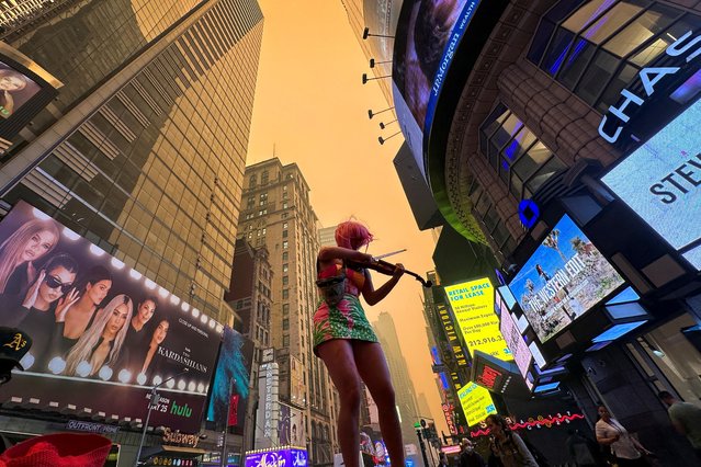 A climate change activist plays a violin in Times Square as Manhattan is shrouded in haze and smoke which drifted south from wildfires in Canada, in New York City, New York, U.S., June 7, 2023. (Photo by Maye-E Wong/Reuters)