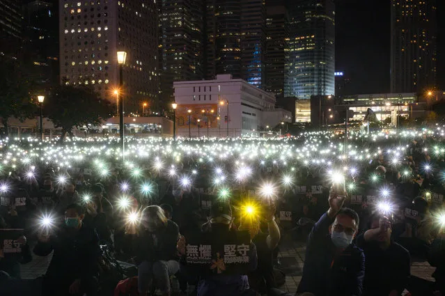 Teachers and pro-democracy supporters light their mobile phones as they take part in a rally to support teachers at Edinburgh Place in the Central district of Hong Kong on January 3, 2020. Hong Kong has been battered by nearly seven months of unrest – its biggest political crisis in decades – which has seen millions come out on the streets demanding greater democratic freedoms. (Photo by Philip Fong/AFP Photo)