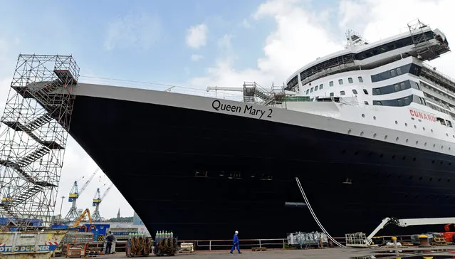 A worker passes by the ocean liner Queen Mary II in a dock at Blohm&Voss shipyard in Hamburg, Germany, June 14, 2016. (Photo by Fabian Bimmer/Reuters)