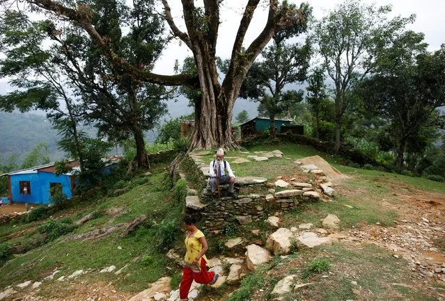 Durga Kami, 68, who is studying in the tenth grade at Shree Kala Bhairab Higher Secondary School, takes a rest as he walks to school in Syangja, Nepal, June 5, 2016. (Photo by Navesh Chitrakar/Reuters)