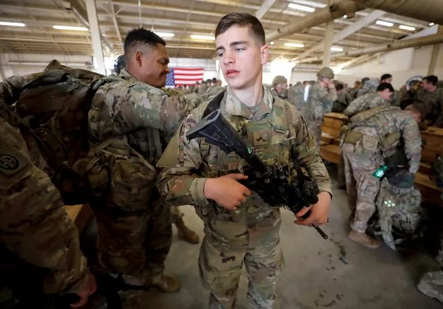 A U.S. Army paratroopers of an immediate reaction force from the 2nd Battalion, 504th Parachute Infantry Regiment, 1st Brigade Combat Team, 82nd Airborne Division, help one another prepare for their departure aboard a C-17 transport aircraft leaving Fort Bragg, North Carolina, U.S. January 1, 2020. (Photo by Jonathan Drake/Reuters)