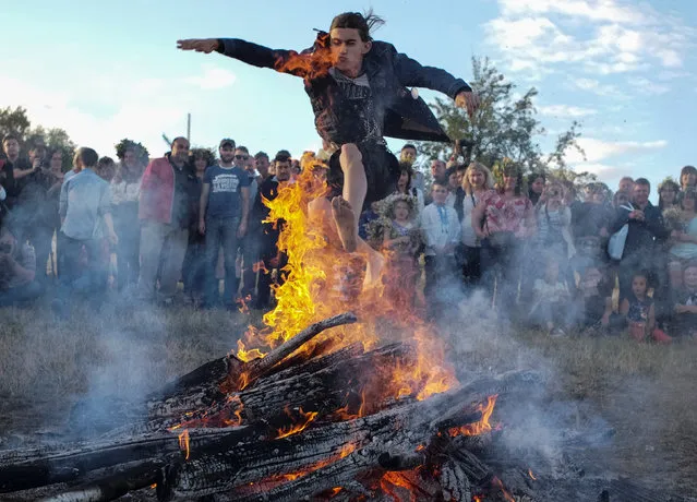 A man jumps over a campfire during a celebration on the traditional Ivana Kupala (Ivan the Bather) holiday, in Kiev, Ukraine, July 6, 2017. The ancient tradition, originating from pagan times, is marked with grand overnight festivities during which people sing and dance around campfires, believing it will purge them of their sins and make them healthier. (Photo by Gleb Garanich/Reuters)
