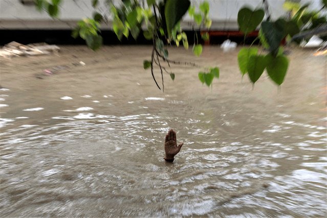 A Hindu priest shows the level of flood waters inside a temple after a rise in the water level of the river Yamuna due to heavy monsoon rains, in New Delhi, India on July 13, 2023. (Photo by Adnan Abidi/Reuters)