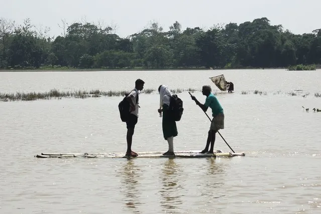 A man transports school students on a bamboo raft across a flooded area following heavy rains in Sylhet on May 24, 2022. At least four million people have been affected by the worst floods in Bangladesh's northeast for nearly two decades, the United Nations said on May 23. (Photo by Mamun Hossain/AFP Photo)