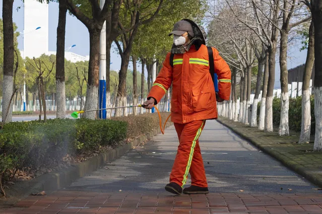 In this Tuesday, January 28, 2020, file photo, a worker wearing a face mask sprays disinfectant along a path in Wuhan in central China's Hubei Province. Face masks are in short supply in parts of the world as people try to stop the spread of a new virus from China. Health officials recommend strap-on medical masks for people being evaluated for the new virus, their household members and caregivers. (Photo by Arek Rataj/AP Photo/File)