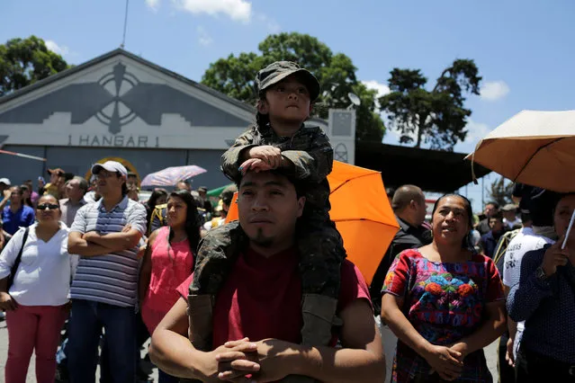 A girl dressed as a soldier sits on the shoulders of a man as they attend a military parade during Army Day celebrations, at the Air Force headquarters in Guatemala City, Guatemala, July 3, 2016. (Photo by Saul Martinez/Reuters)