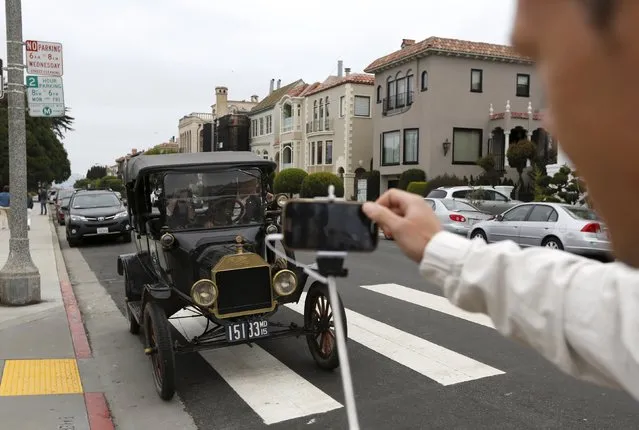 A tourist snaps a photograph of a 1915 Ford Model T after it arrived from Detroit at the Palace of Fine Arts in San Francisco, California August 19, 2015. The 3,500 mile, 34-day road trip recreated the cross country journey made by Edsel Ford 100 years ago, when he arrived at the Palace of Fine Arts for the 1915 World's Fair. (Photo by Robert Galbraith/Reuters)