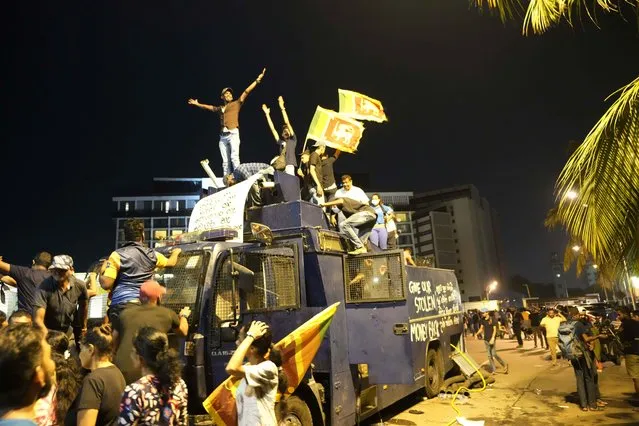 Protesters stand on a vandalised police water canon truck and shout slogans at the entrance to president's official residence in Colombo, Sri Lanka, Saturday, July 9, 2022. (Photo by Eranga Jayawardena/AP Photo)