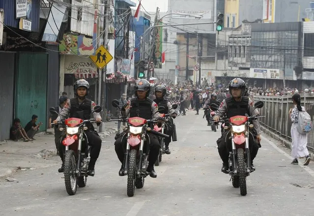 Indonesian policemen patrol on motorbikes after clashing with residents, at Kampung Pulo district in Jakarta, August 20, 2015. (Photo by Reuters/Beawiharta)