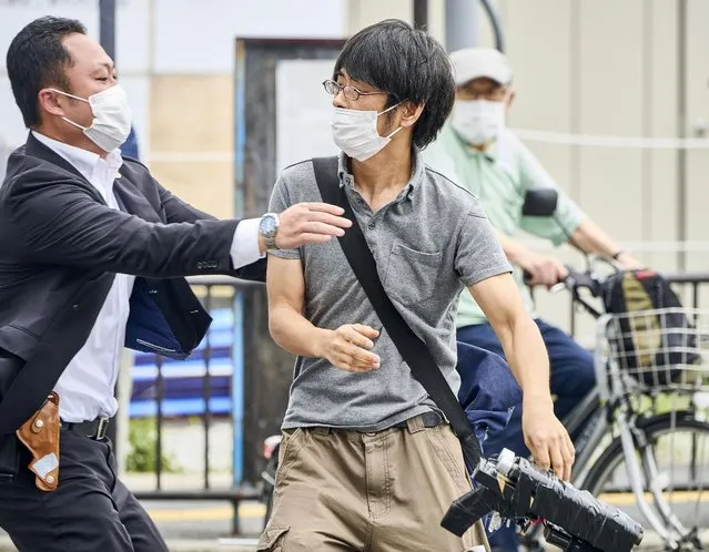 Tetsuya Yamagami, center, holding a weapon, is detained near the site of gunshots in Nara, western Japan Friday, July 8, 2022. Former Prime Minister Shinzo Abe was assassinated Friday on a street in western Japan by Yamagami, a gunman who opened fire on him from behind as he delivered a campaign speech – an attack that stunned the nation that has some of the strictest gun control laws anywhere. (Photo by Nara Shimbun/Kyodo News via AP Photo)