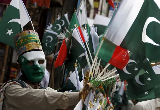 A Pakistan flag seller wears a mask as he displays his flags at the Qissa Khwani Bazar in Peshawar, Pakistan August 10, 2015. Pakistan's National Day is celebrated August 14 annually to commemorate the day Pakistan achieved independence and was declared a sovereign nation. (Photo by Khuram Parvez/Reuters)