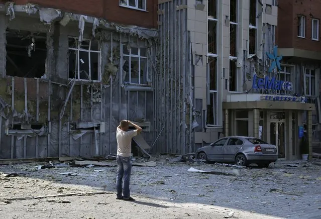 A local resident reacts as he inspects the damage after shelling in Donetsk, eastern Ukraine, Thursday, August 7, 2014. Fighting in the rebel stronghold of Donetsk claimed more civilian casualties, bringing new calls from Russian nationalists for President Vladimir Putin to send in the army. (Photo by Sergei Grits/AP Photo)