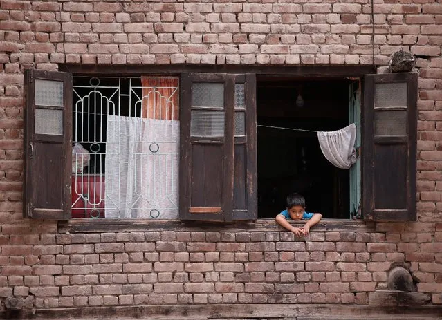 A boy looks out from a window of his house during a curfew in Srinagar, July 17, 2016. (Photo by Danish Ismail/Reuters)