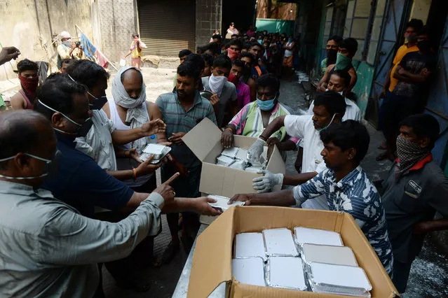 Volunteers of a Non-Governmental Organisation distribute food to migrant workers during the first day of a 21-day government-imposed nationwide lockdown as a preventive measure against the COVID-19 coronavirus, in Chennai on March 25, 2020. India's billion-plus population went into a three-week lockdown on March 25, with a third of the world now under orders to stay indoors, as the coronavirus pandemic forced Japan to postpone the Olympics until next year. (Photo by Arun Sankar/AFP Photo)