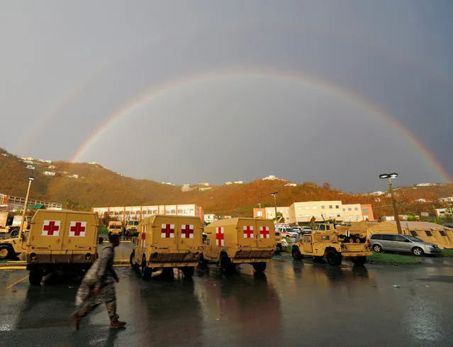 A soldier with the U.S. Army's 602nd Area Support Medical Company walks past a row of the unit's vehicles while a double rainbow appears in the sky over the U.S. Virgin Island's main hospital, Schneider Regional Medical Center, in Charlotte Amalie, St. Thomas, U.S. Virgin Islands September 14, 2017. (Photo by Jonathan Drake/Reuters)