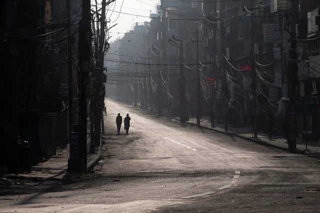People walk along an empty road during an emergency nationwide lock down in Kathmandu, Nepal, 24 March 2020. After the confirmation of the second COVID-19 case in Nepal, the government has decided to enforce a week-long lock down from 24 March to 31 March 2020 in an effort to contain the spread of the coronavirus. (Photo by Narendra Shrestha/EPA/EFE)