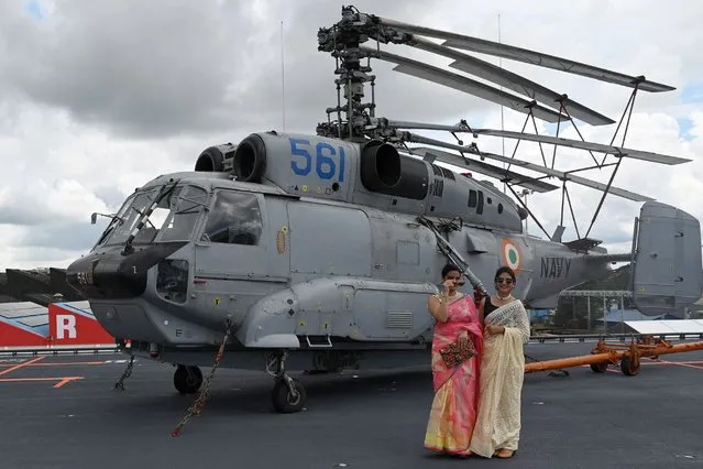 Women stand next to Komoho Helicopter on the deck of the Indian indigenous aircraft carrier INS Vikrant during its commissioning at Cochin Shipyard in Kochi on September 2, 2022. India debuted its first locally made aircraft carrier on September 2, a milestone in government efforts to reduce its dependence on foreign arms and counter China's growing military assertiveness in the region. (Photo by Arun Sankar/AFP Photo)