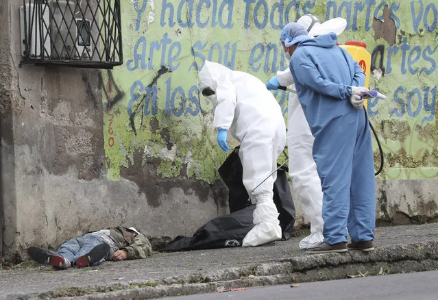 Forensic investigators look at the body of a man infected with the new coronavirus who collapsed on the street and died, according to Police Captain Diego Lopez, in Quito, Ecuador, Tuesday, May 5, 2020. (Photo by Dolores Ochoa/AP Photo)