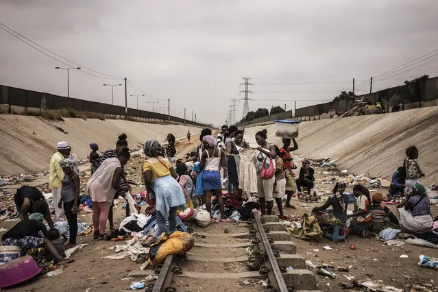 Hawkers sell their products in an improvised market across a train track in the Viana district in Luanda, on August 22, 2017. With current president Dos Santos standing down after the election, the ruling MPLA party – which has held power since 1975 – is expected to win again and install his chosen successor, Joao Lourenco, as head of state. (Photo by Marco Longari/AFP Photo)
