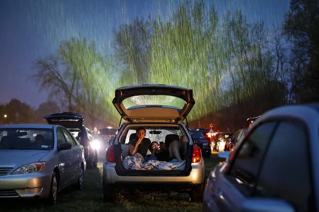 Guests watch “Trolls World Tour”, in the rain at the Four Brothers Drive In Theatre amid the coronavirus pandemic, Friday, May 15, 2020, in Amenia, N.Y. (Photo by John Minchillo/AP Photo)