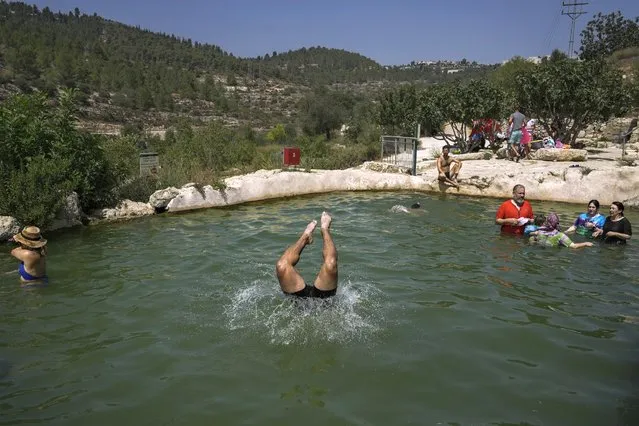 Israelis and Palestinians swim in Ein Haniya spring, in Jerusalem, Monday, August 29, 2022. Israel and the Palestinian territories are in the grip of a heat wave this week, with temperatures hitting 40 C (over 100 F) in Jerusalem, and soaring even higher in more arid regions. (Photo by Mahmoud Illean/AP Photo)