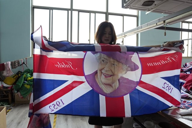 General manager Fan Aiping holds up one of the flag with the Queen's image at the Shaoxing Chuangdong Tour Articles Co. factory in Shaoxing, in eastern China's Zhejiang province, Friday, September 16, 2022. (Photo by Ng Han Guan/AP Photo)