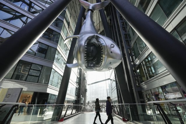 People pass by a shark artwork hung on poles, which the artist said represents poaching of this species, at a mall in Beijing on Tuesday, January 21, 2025. (Photo by Aaron Favila/AP Photo)