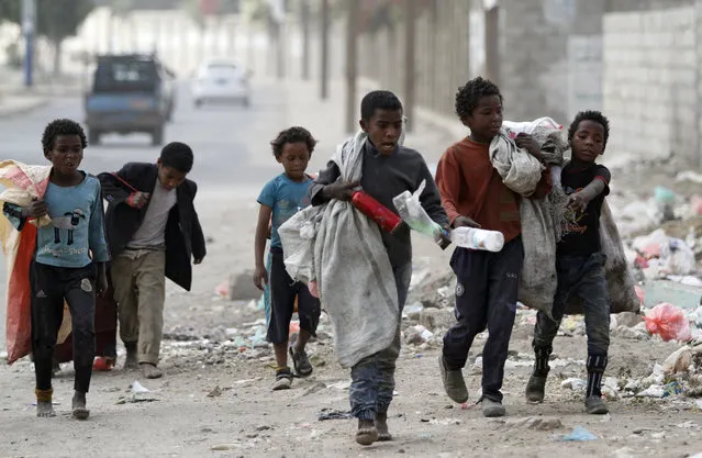 Children walk as they collect empty plastic bottles in a street in Sanaa, Yemen on November 21, 2019. (Photo by Mohamed al-Sayaghi/Reuters)