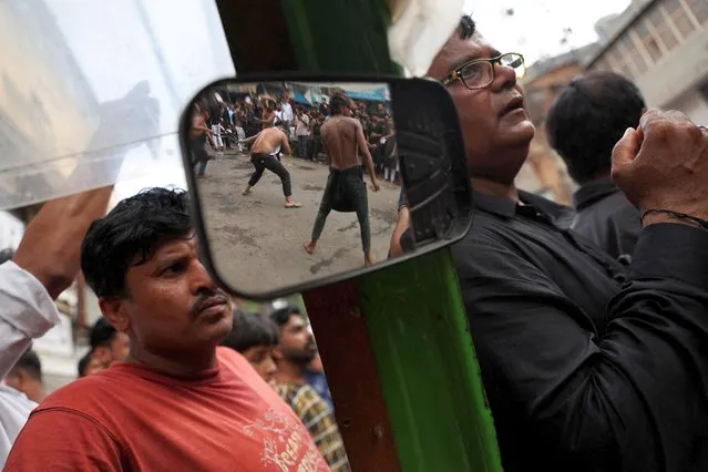 People watch as Shi'ite Muslims flagellate themselves during a Muharram procession marking Ashura, in the old quarters of Delhi, India on August 9, 2022. (Photo by Anushree Fadnavis/Reuters)
