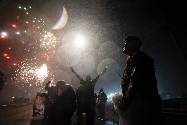 People watch fireworks while rain falls at the Saint “Gauchito” Gil sanctuary in Mercedes, Corrientes, Argentina, late Sunday, January 7, 2024. Every Jan. 8, devotees from across the country visit his sanctuary to ask for miracles or give him thanks. (Photo by Natacha Pisarenko/AP Photo)