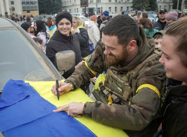 Ukrainian serviceman gives an autograph to locals resident as people celebrate after Russia's retreat from Kherson, in central Kherson, Ukraine on November 12, 2022. (Photo by Lesko Kromplitz/Reuters)