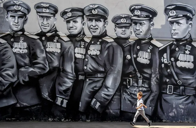 A boy runs in front of a graffiti dedicated to WWII Soviet pilots on the Day of Remembrance and Sorrow on the 79th anniversary of the Nazi invasion of the Soviet Union, in downtown Moscow on June 22, 2020. (Photo by Yuri Kadobnov/AFP Photo)